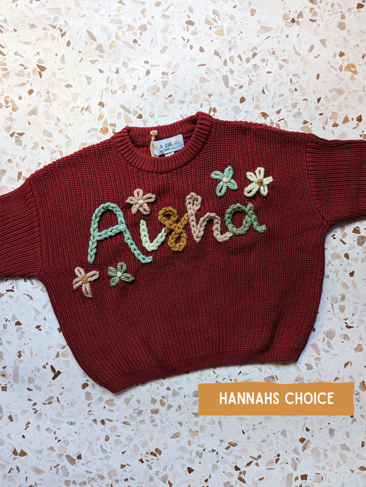 hand embroidered name knit with multicolour yarn spelling childrens name with flowers surrounding